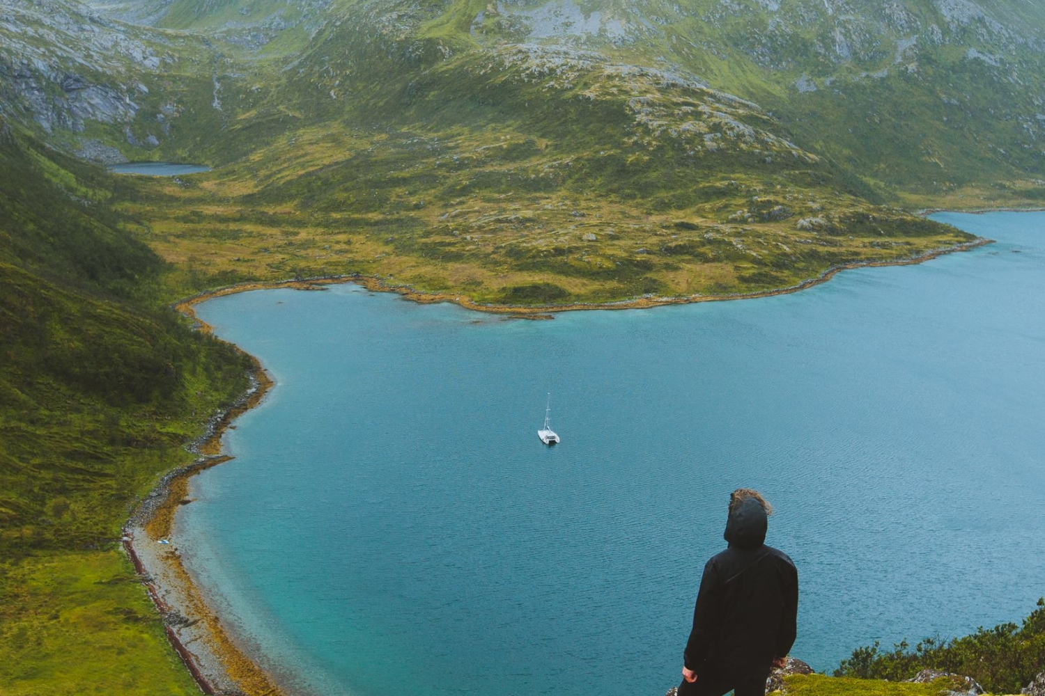 Mann som ser på utsikt over hav, fjell og fjord