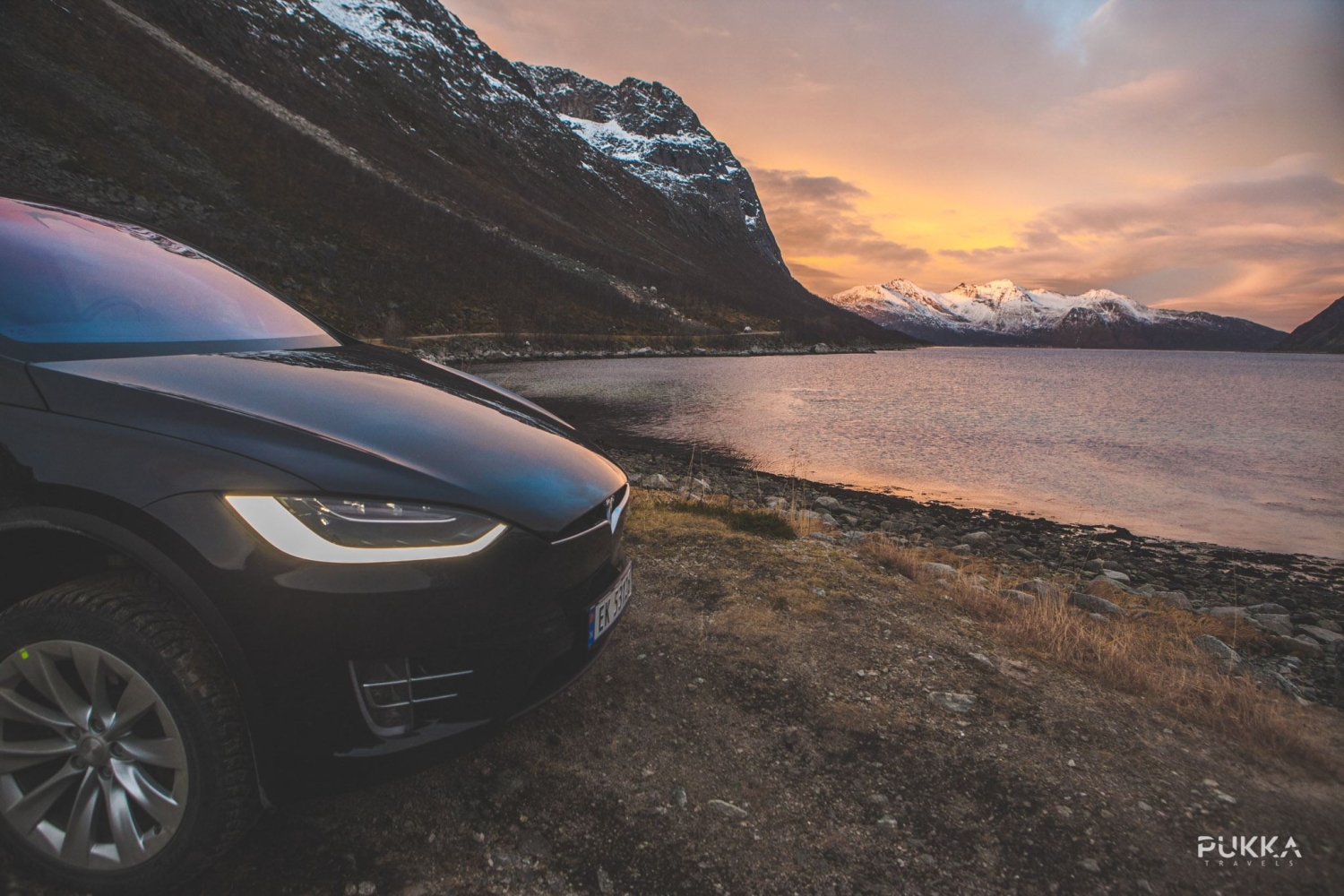 Tesla with colourful sky, sea and mountains in the background