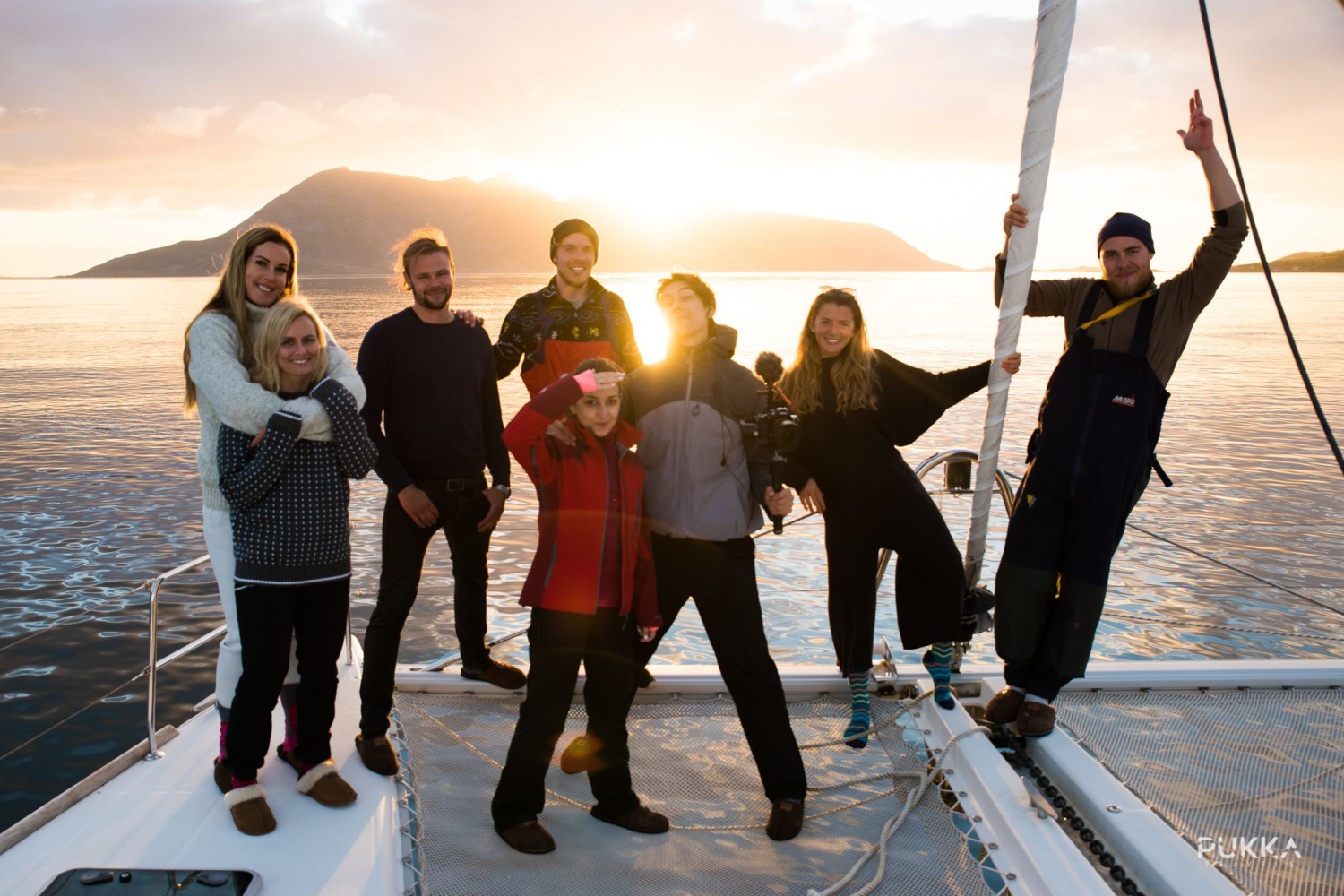a group of  people on deck with the midnight sun in the background