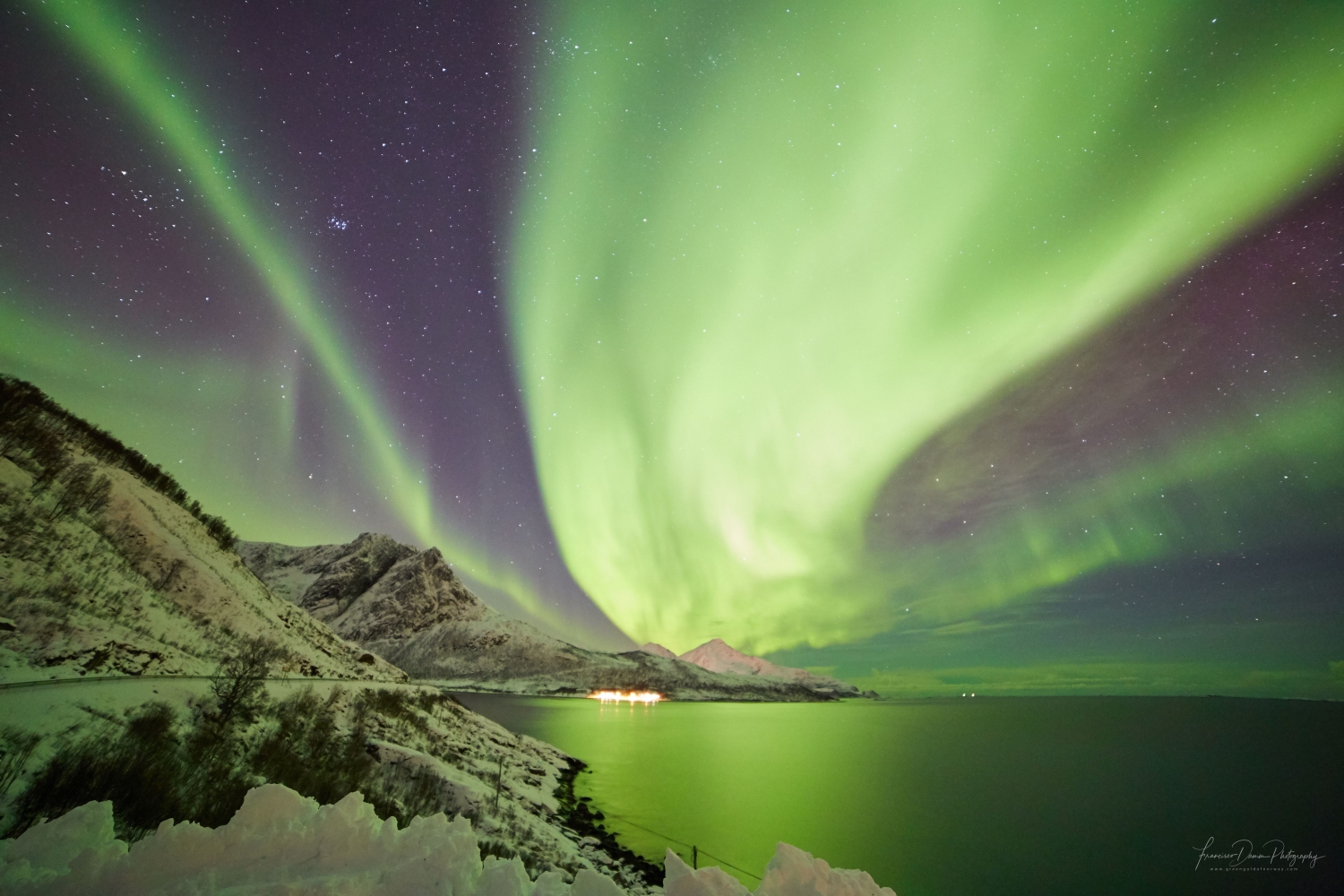 strong northern lights covering the whole sky over mountains and sea