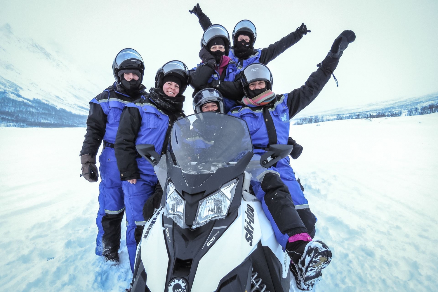 people posing around a snowmobile