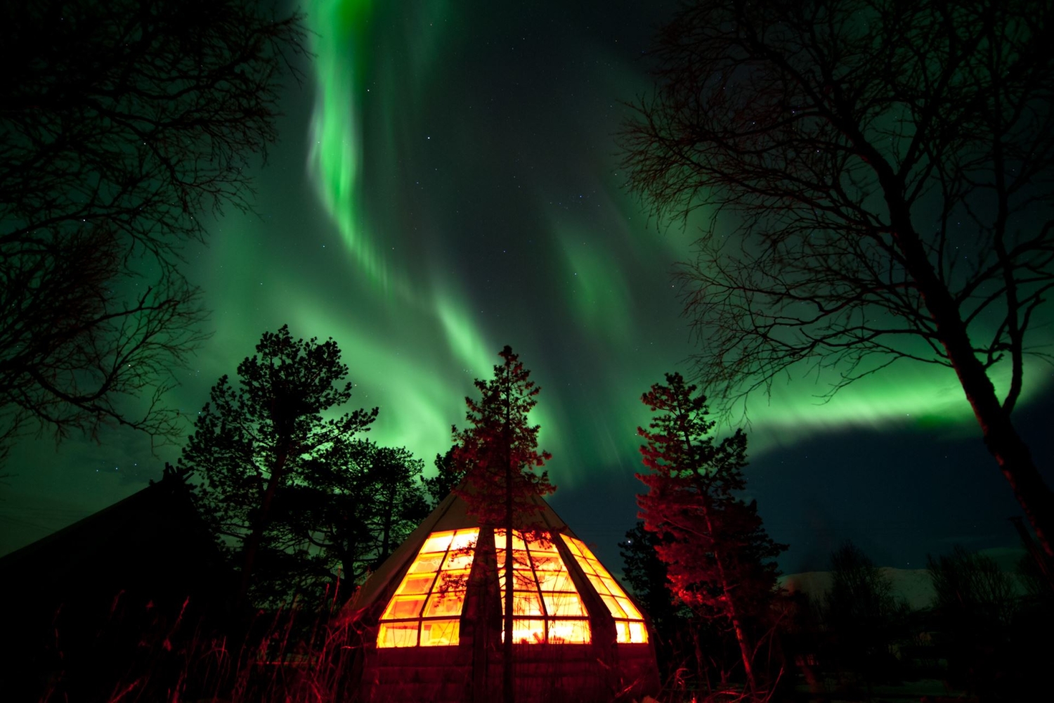Lit gamme hut with Norhtern Lights on the sky avbove