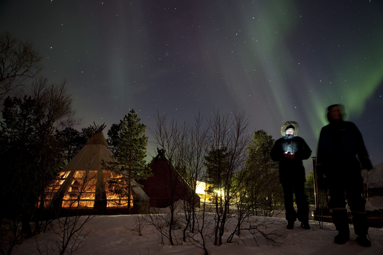 People standing outside of the gamme hut watching the Northern Lights