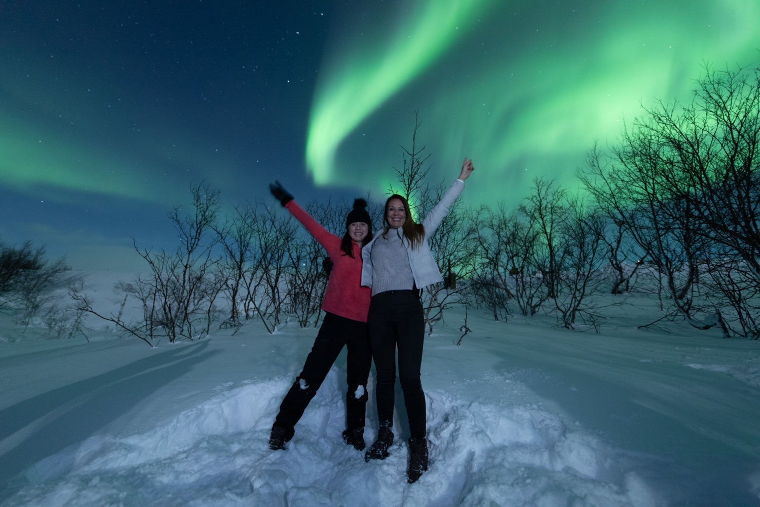 two people under a sky full of northern lights