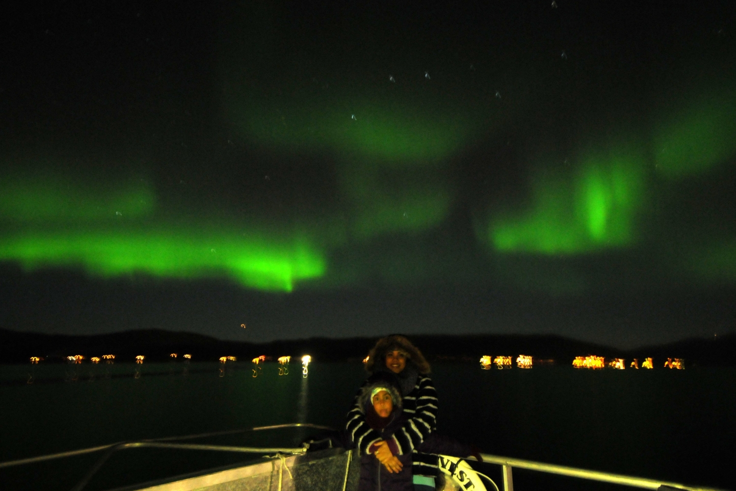 Couple out on deck with the Northern Lights in the background