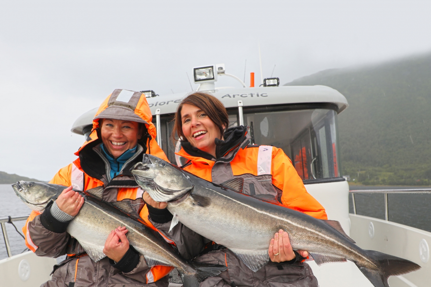 2 women smiling and holding 2 fish