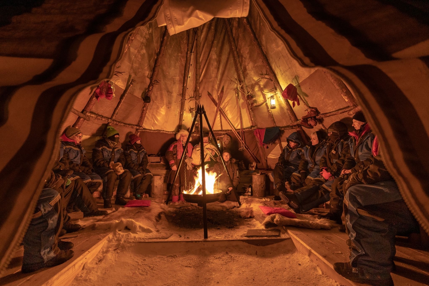 Guests gathered around a bonfire inside a Sami lavvu