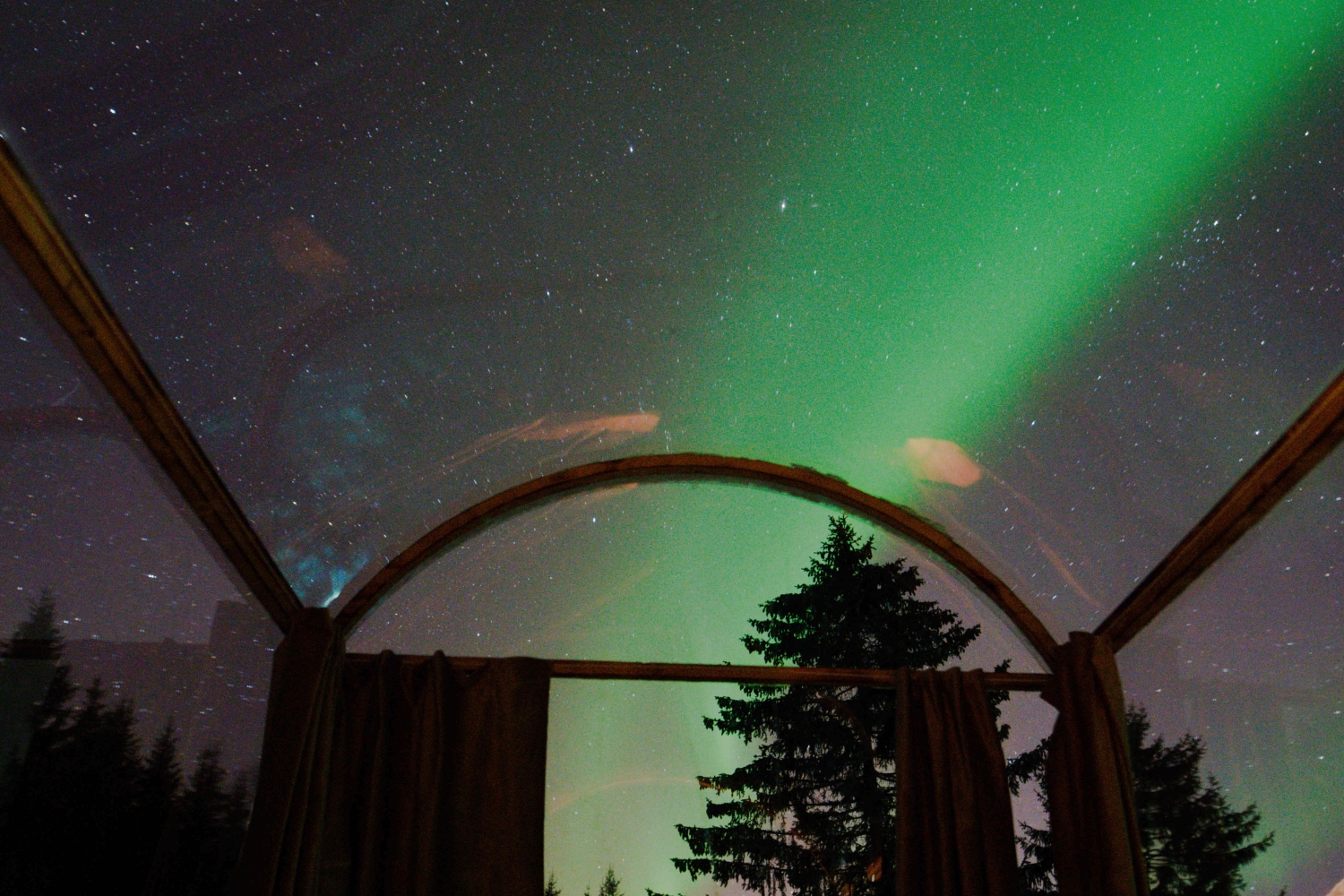 glass cabin with northern lights above