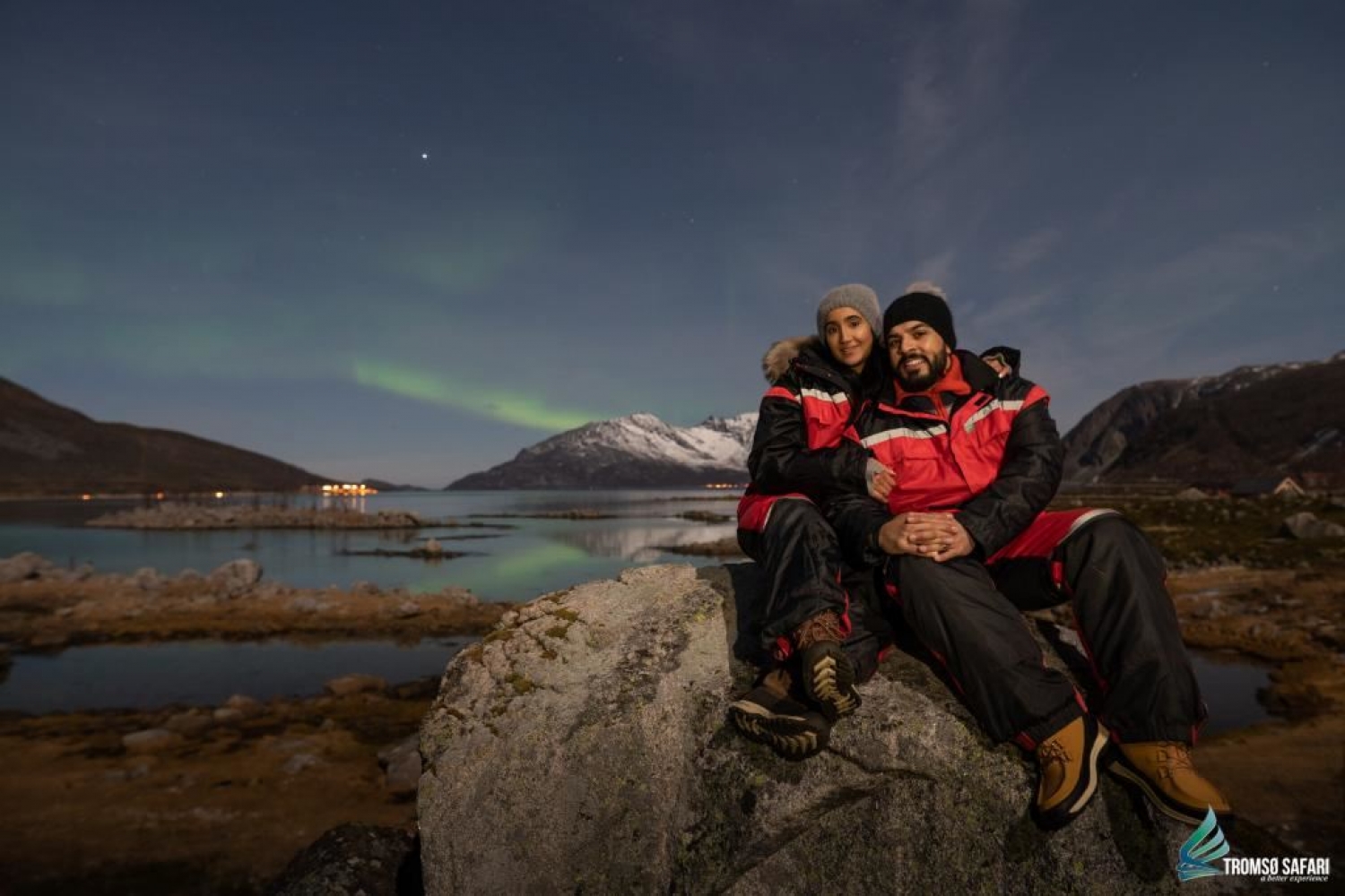 to personer som nyter nordlyset over fjorden