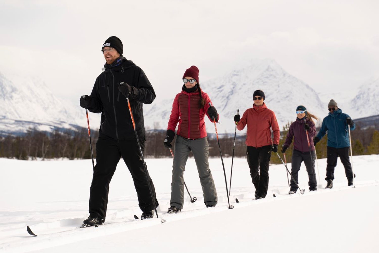 five people cross-country skiing with the Lyngen Alps in the background