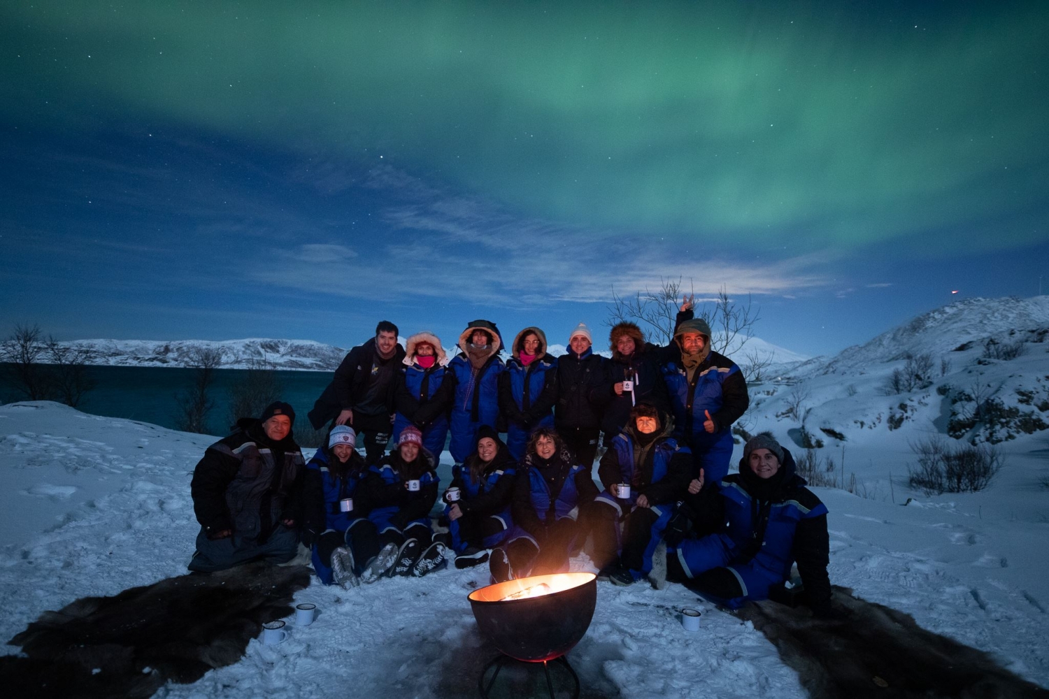 group of people under a sky full of northern lights