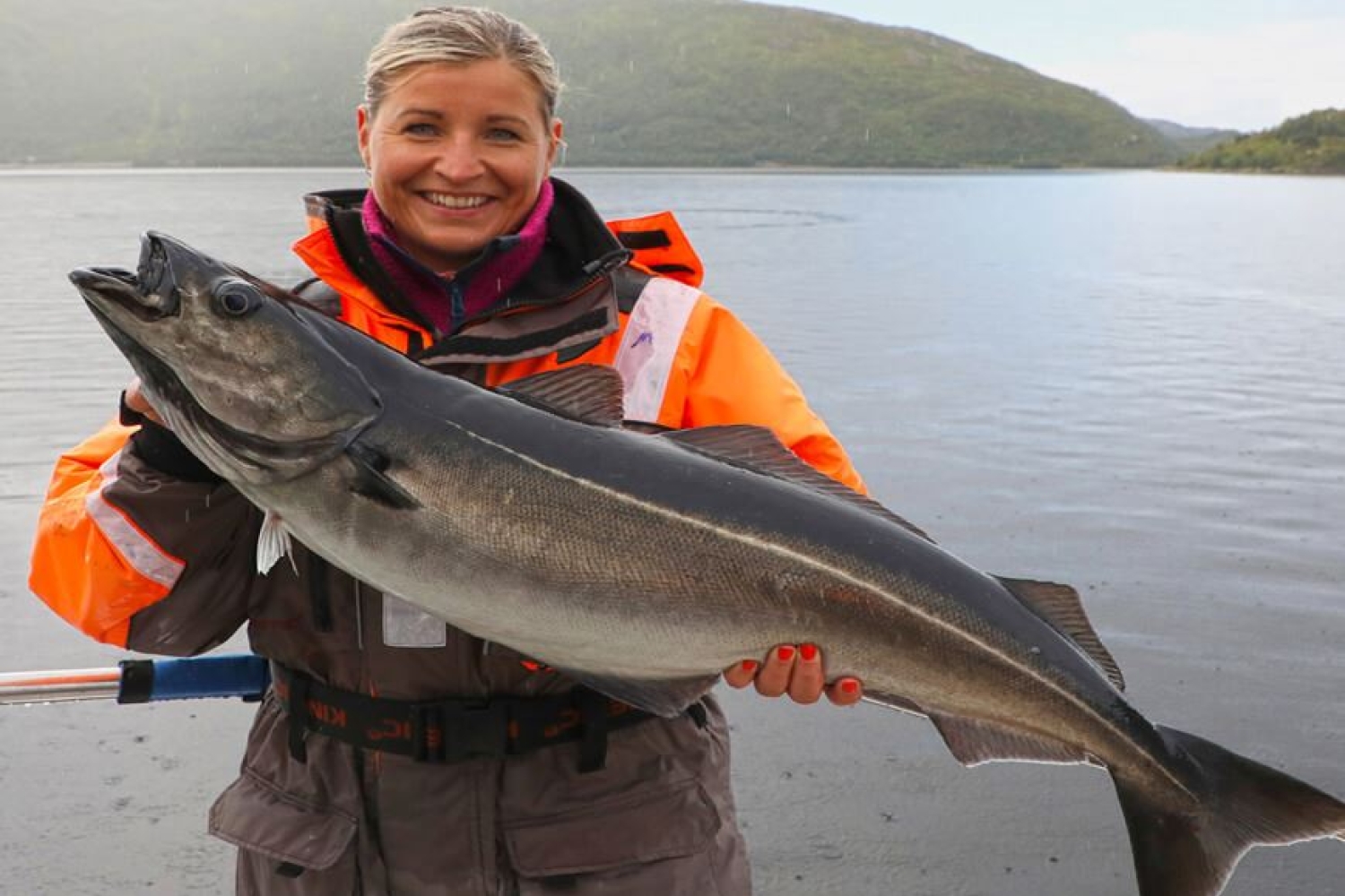 Dame som holder en fisk på fisketur med Explore the Arctic