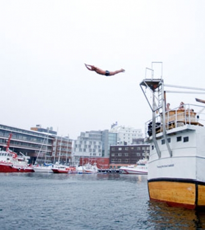 Man jumping in the water from spaboat in Tromsø